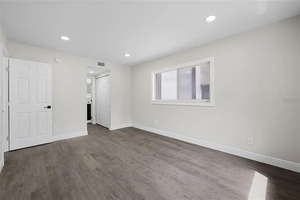a view of an empty room with wooden floor and a window