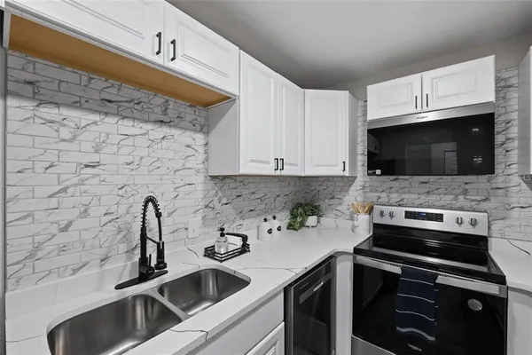 a kitchen with stainless steel appliances a sink a stove a microwave a sink and cabinets