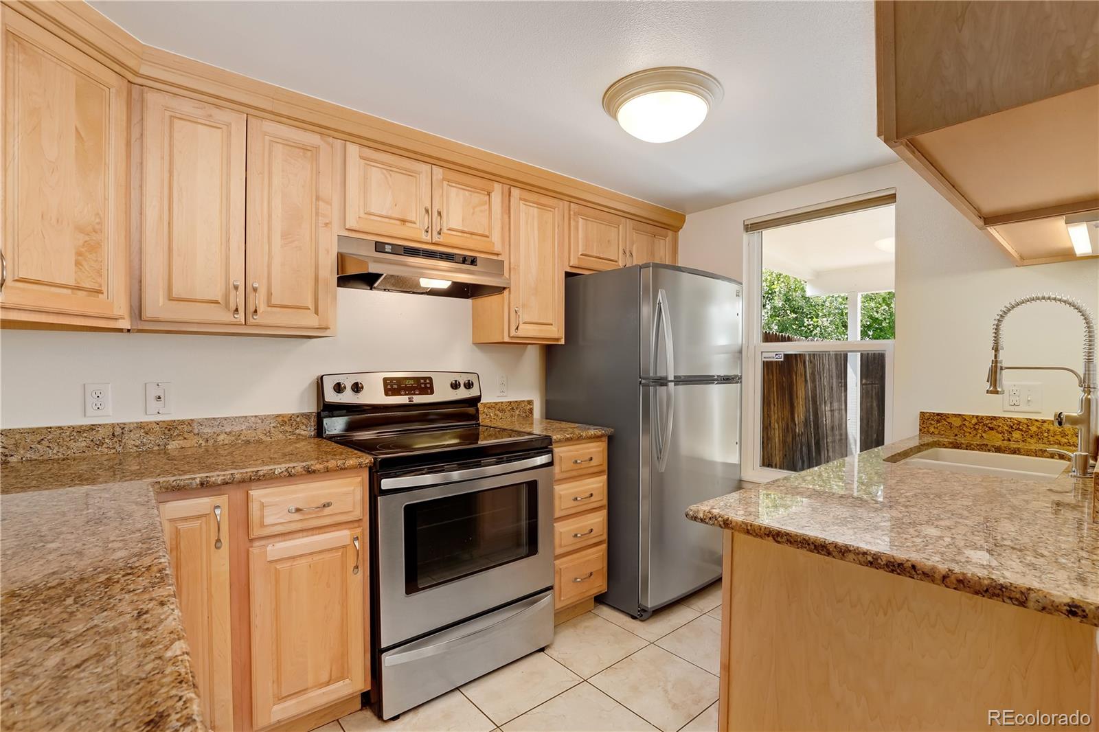 8760 Independence Way Arvada, CO 80005 - Photo 19 of 40 a kitchen with granite countertop a stove sink and refrigerator