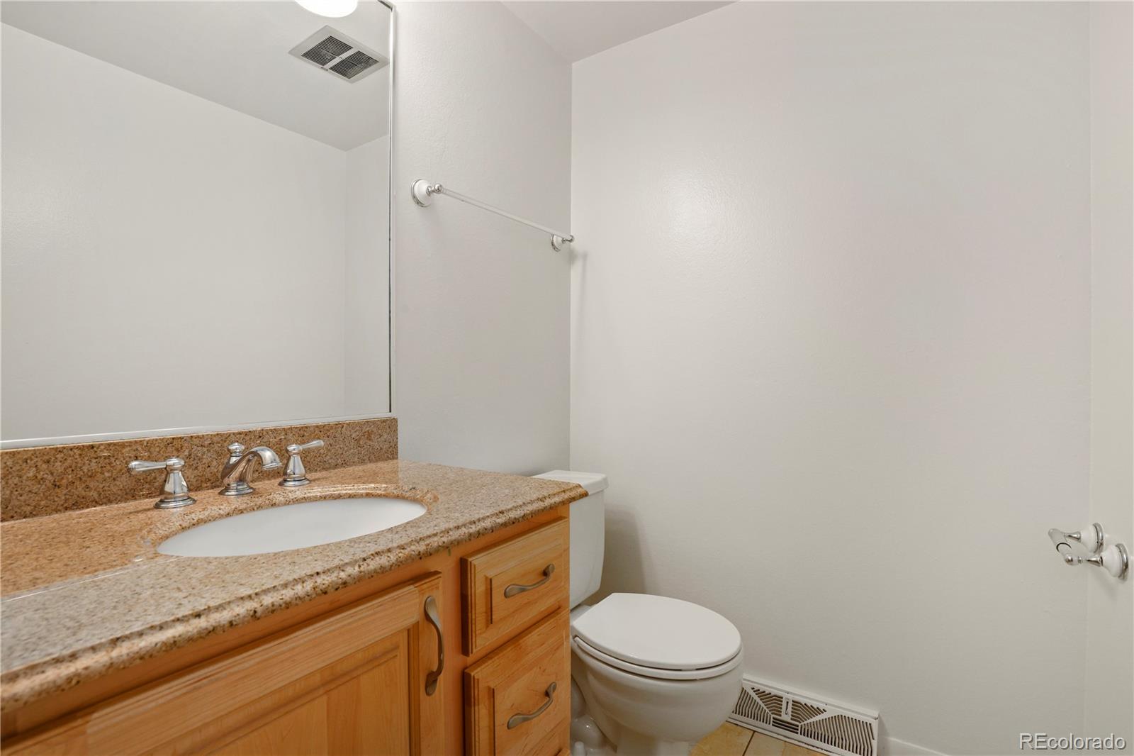 8760 Independence Way Arvada, CO 80005 - Photo 23 of 40 a bathroom with a granite countertop sink toilet and a mirror