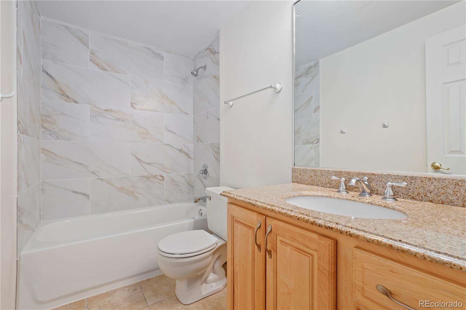 8760 Independence Way Arvada, CO 80005 - Photo 24 of 40 a bathroom with a granite countertop sink toilet and shower