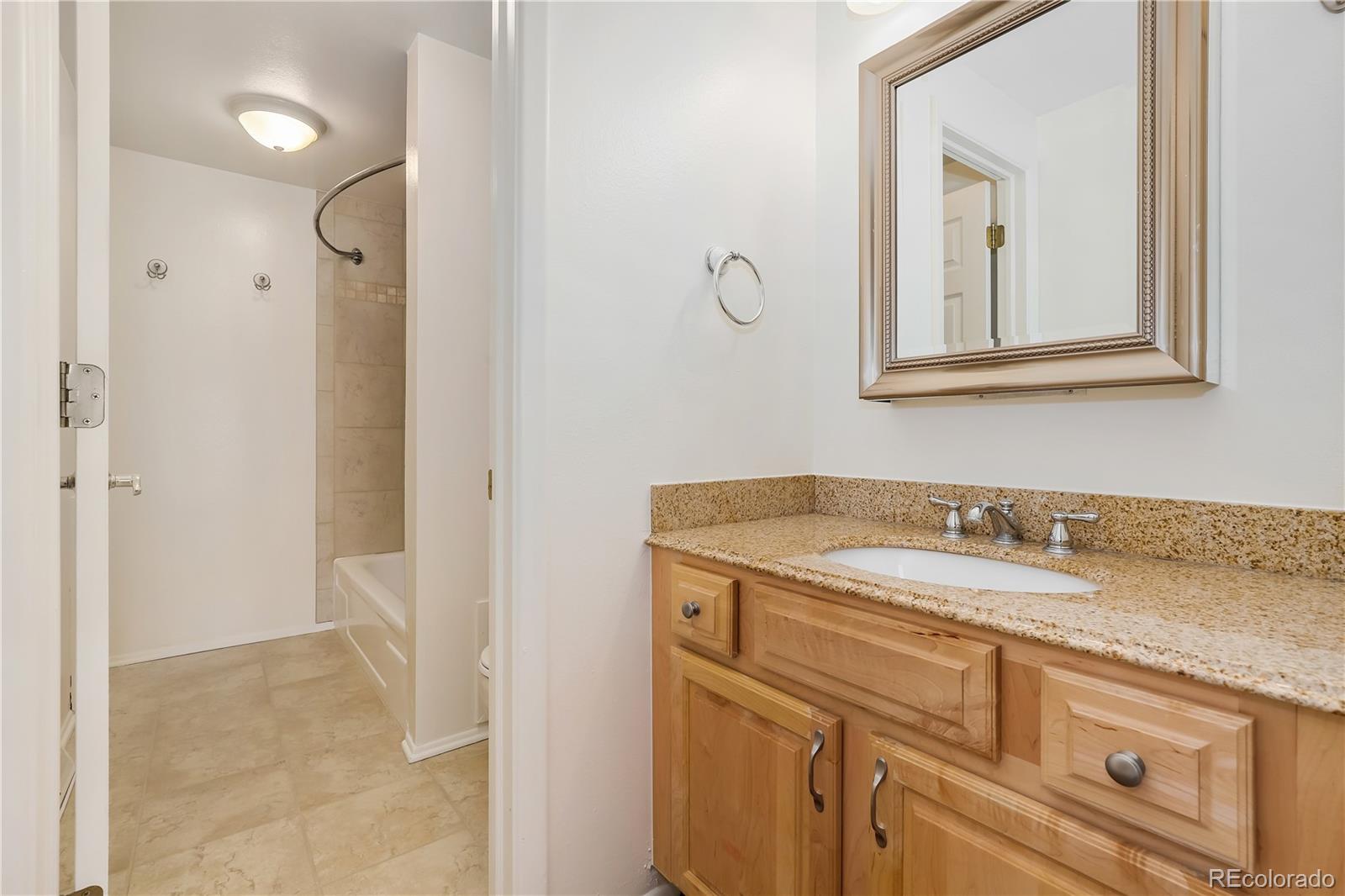 8760 Independence Way Arvada, CO 80005 - Photo 32 of 40 a bathroom with a granite countertop sink vanity and mirror