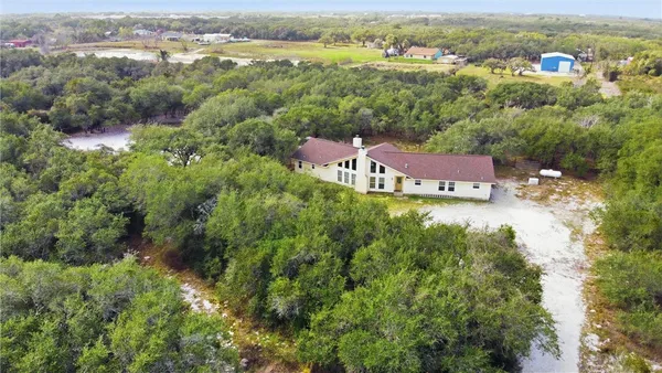 an aerial view of residential houses with outdoor space and trees