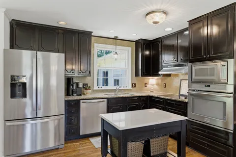a kitchen with stainless steel appliances a stove refrigerator and cabinets