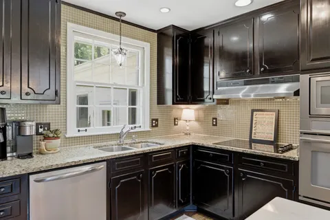 a kitchen with granite countertop a sink stove and cabinets