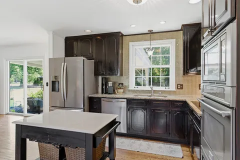 a kitchen with stainless steel appliances granite countertop a refrigerator a sink dishwasher a stove and white countertops with wooden floor