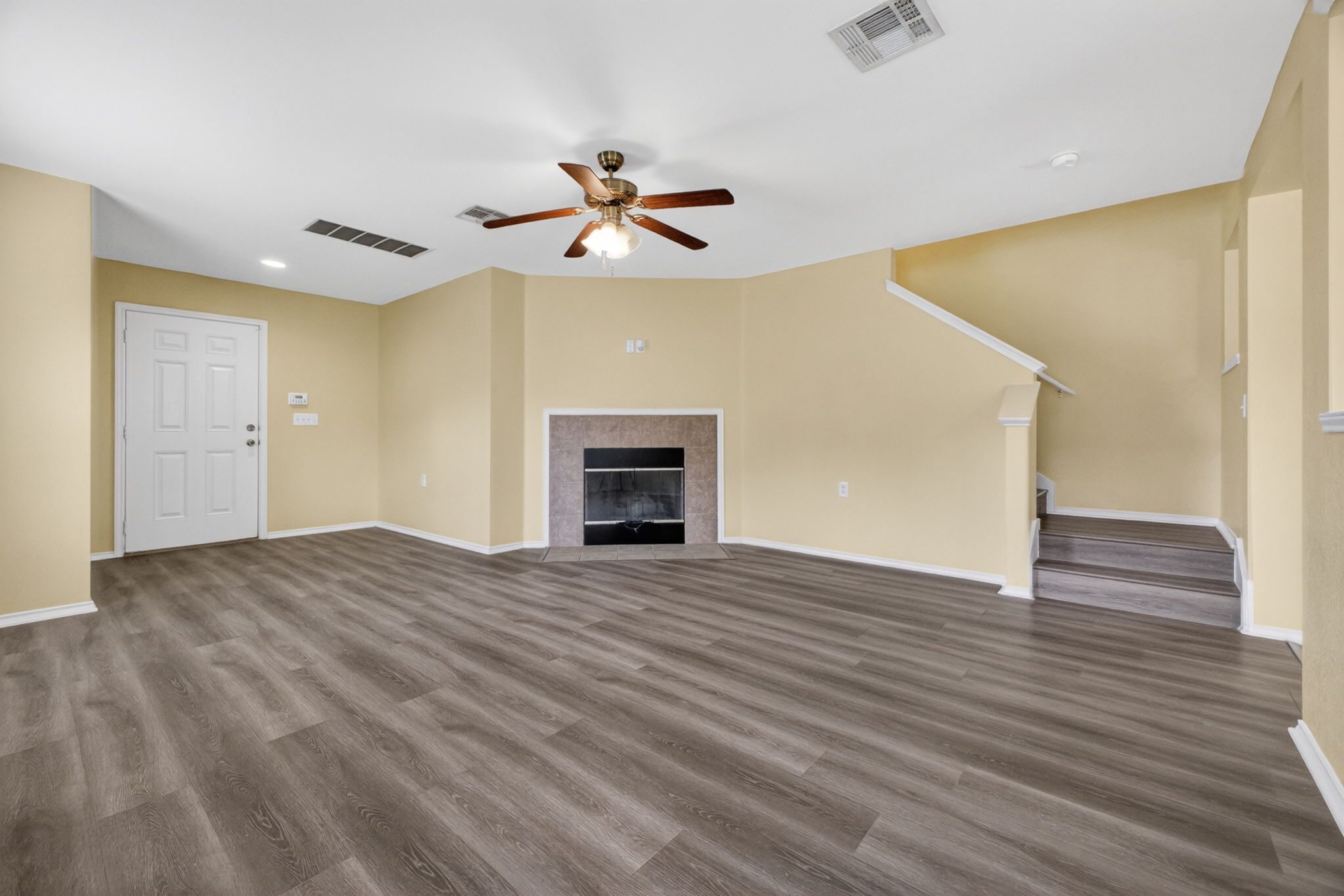 8813 Wiley Way Austin, TX 78747 - Photo 3 of 39 A spacious living area featuring durable laminate flooring, a fireplace, and a welcoming ceiling fan.