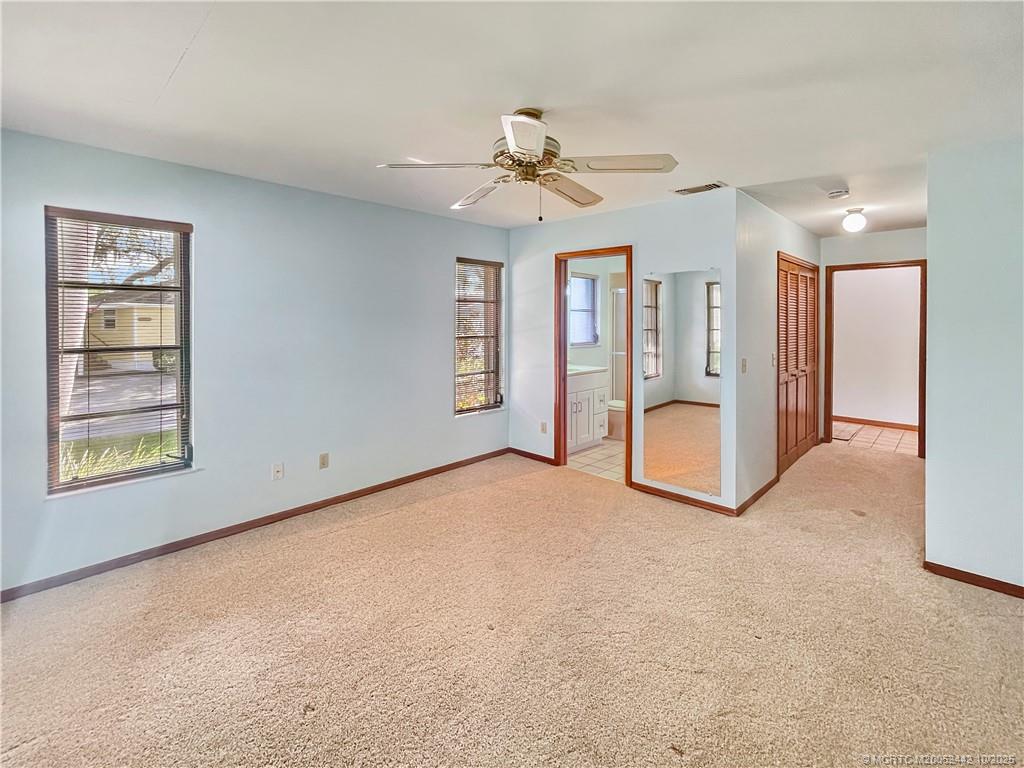 735 Southwest Salerno Road Stuart, FL 34997 - Photo 18 of 27 an empty room with chandelier fan and windows