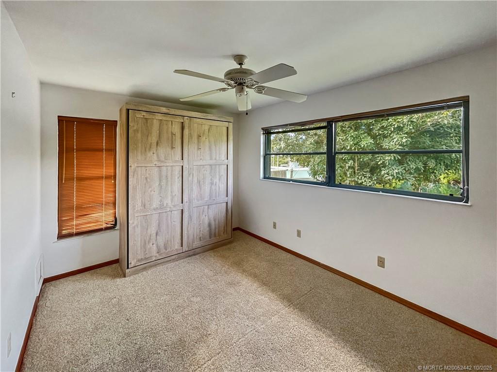 735 Southwest Salerno Road Stuart, FL 34997 - Photo 23 of 27 an empty room with windows and ceiling fan