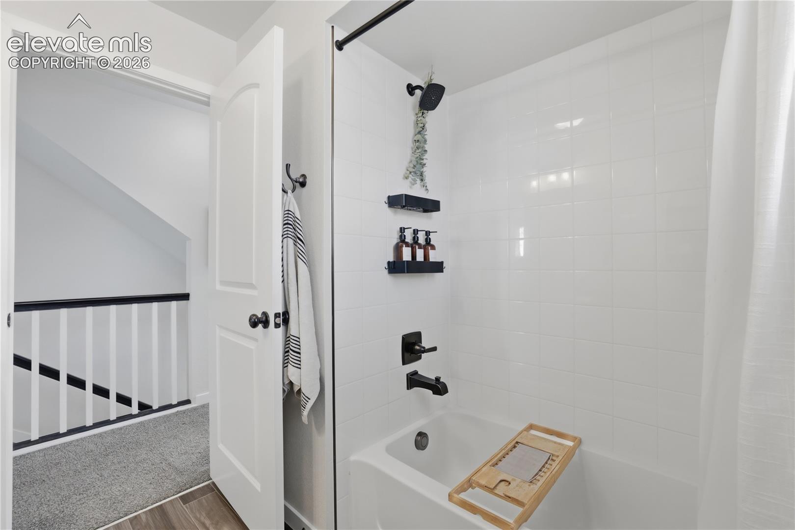 6008 Ashmore Road Colorado Springs, CO 80927 - Photo 29 of 48 Bathtub and shower combination featuring white subway tile surround, matte black fixtures, and a white shower curtain