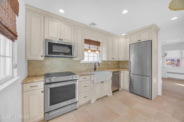 a kitchen with stainless steel appliances granite countertop a refrigerator stove a sink and dishwasher with white cabinets