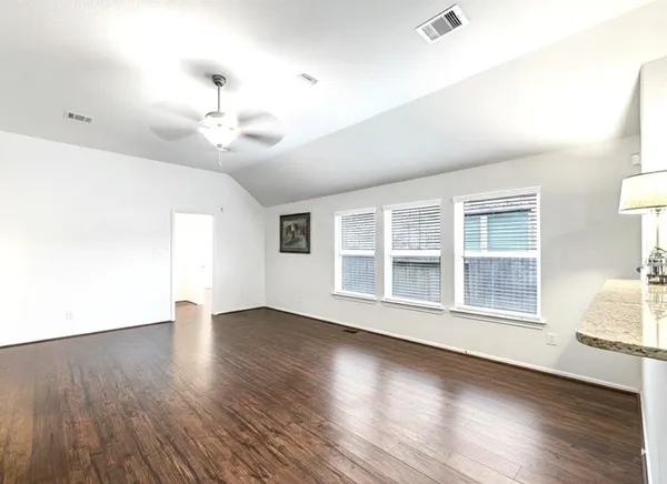 a view of an empty room with wooden floor and a window