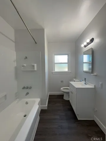 a bathroom with a tub sink toilet and mirror