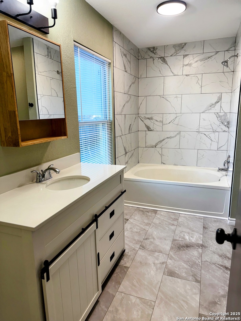 7935 Sonny Ridge San Antonio, TX 78244 - Photo 18 of 22 a bathroom with a bathtub a sink and a mirror