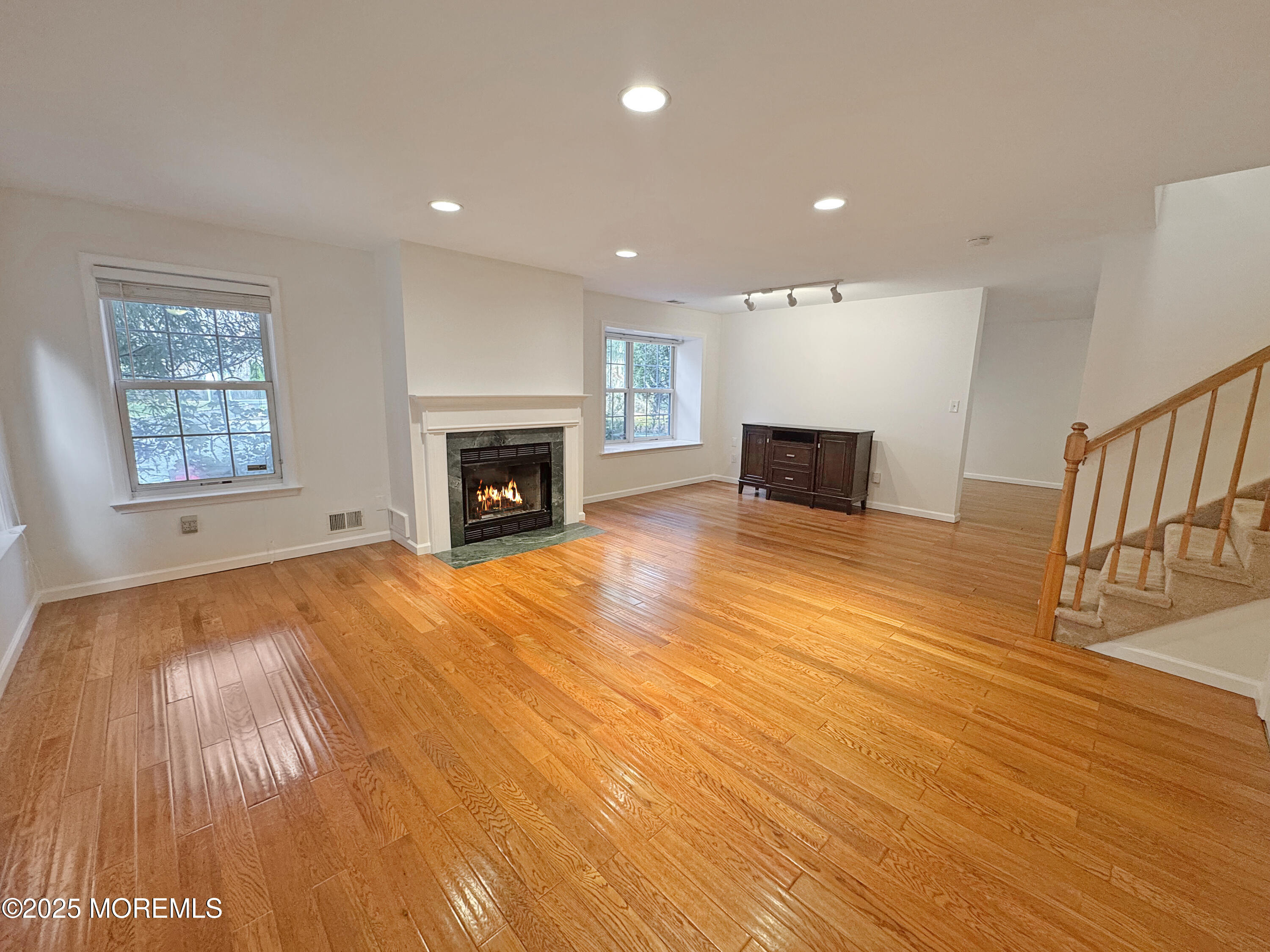 577 Windflower Court Morganville, NJ 07751 - Photo 4 of 27 an empty room with wooden floor and fireplace