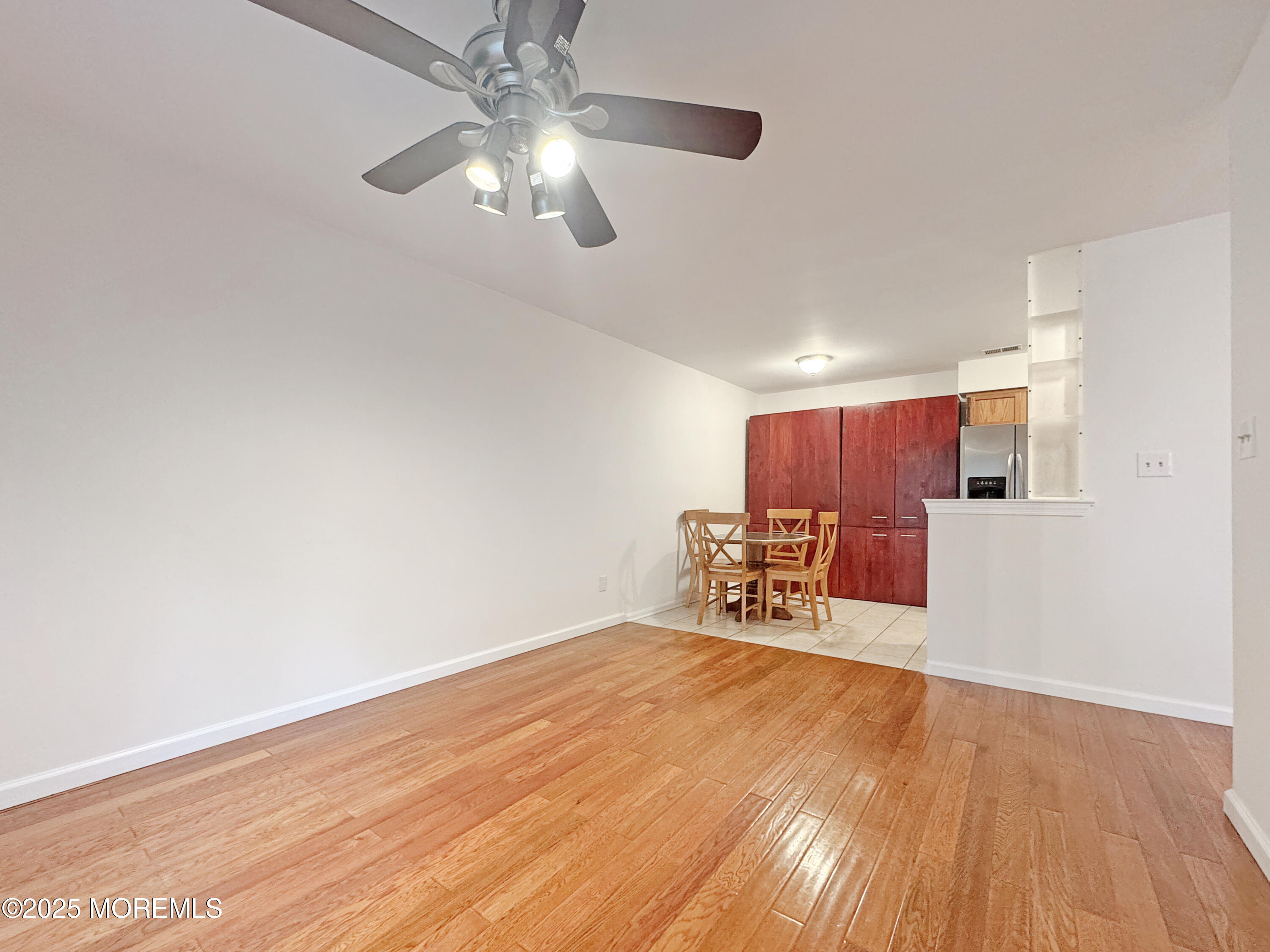 577 Windflower Court Morganville, NJ 07751 - Photo 7 of 27 an empty room with wooden floor fan and windows