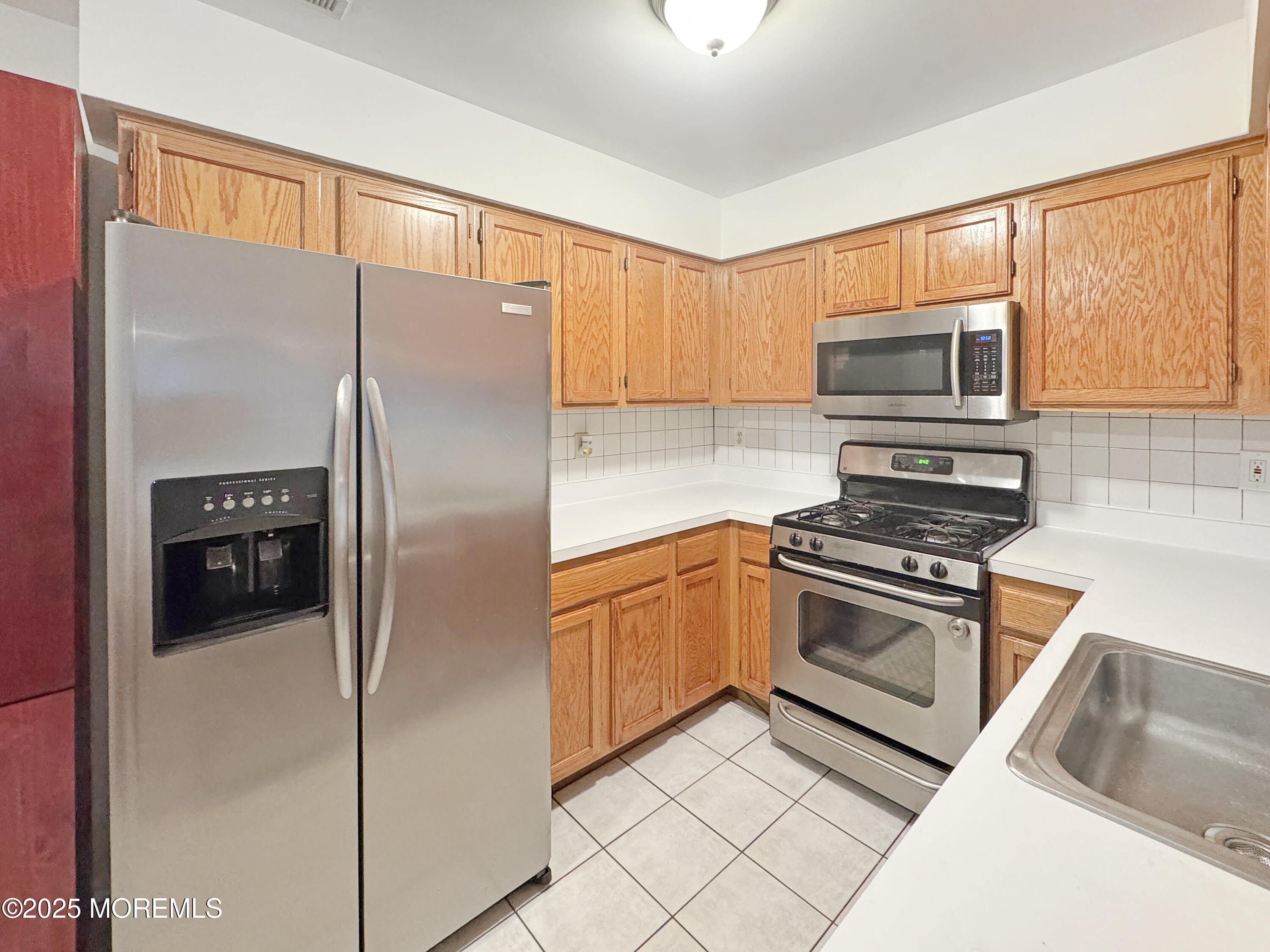 577 Windflower Court Morganville, NJ 07751 - Photo 10 of 27 a kitchen with granite countertop a refrigerator stove and microwave