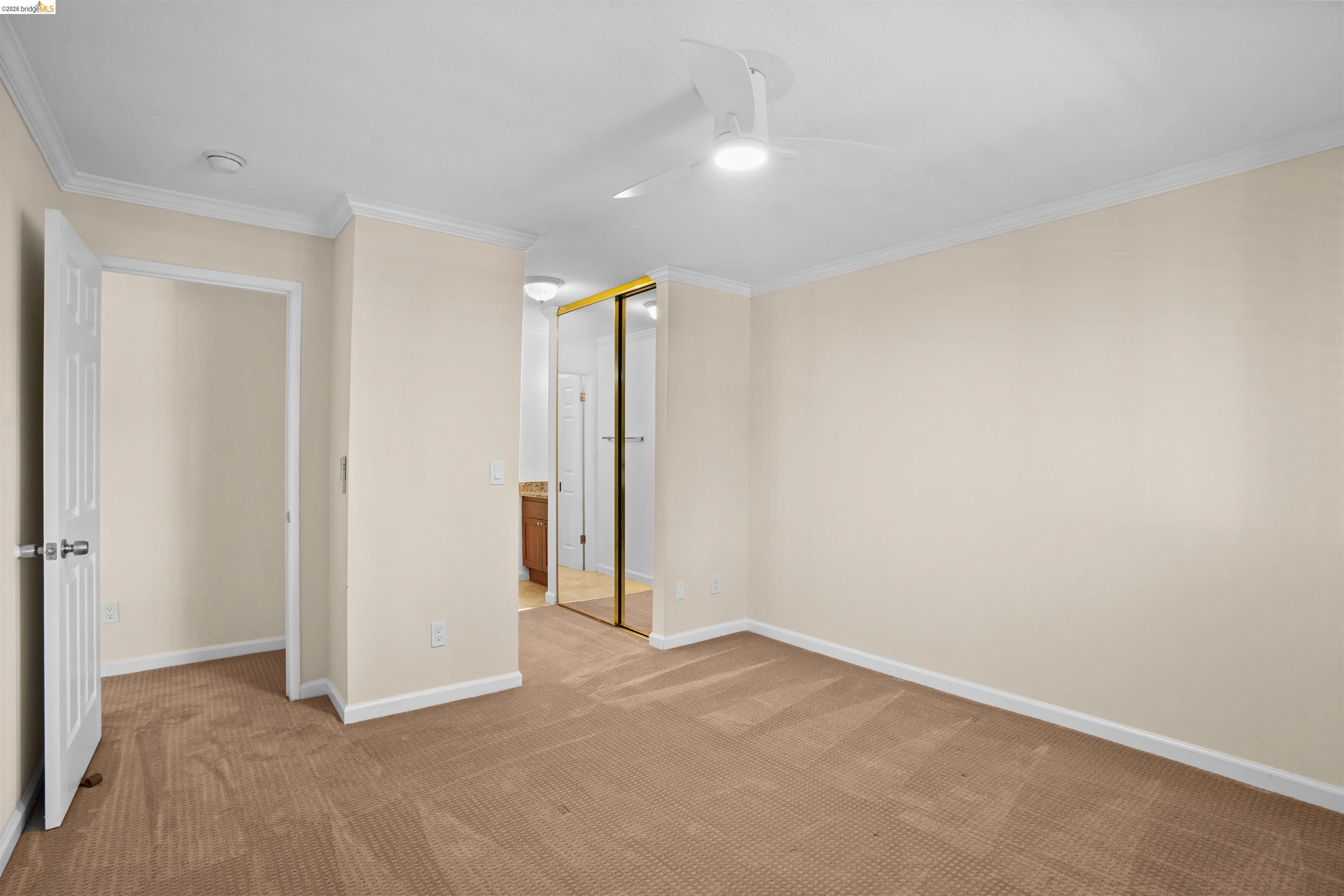 1505 Kirker Pass Road, Unit 214 Concord, CA 94521 - Photo 32 of 55 Carpeted room featuring a ceiling fan with integrated lighting, crown molding, and a partial view of a bathroom vanity with a wood-finish cabinet and mirror