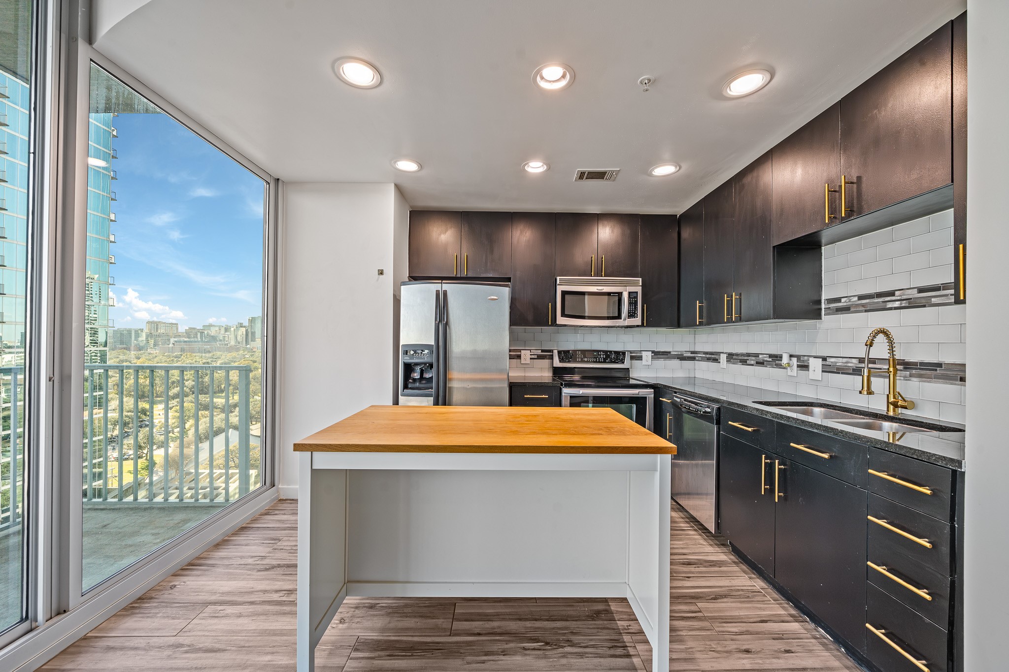 5925 Almeda Road, Unit 11406 Houston, TX 77004 - Photo 7 of 26 a large kitchen with stainless steel appliances kitchen island granite countertop a sink and a stove top oven with wooden floor