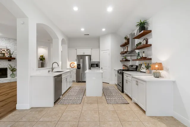 a kitchen with stainless steel appliances kitchen island granite countertop a refrigerator and a sink