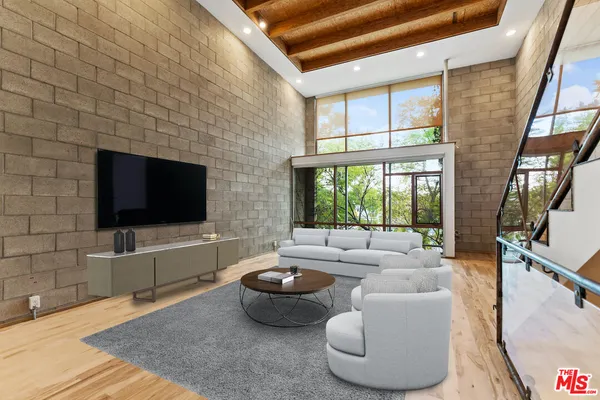 a living room with furniture a flat screen tv and a floor to ceiling window