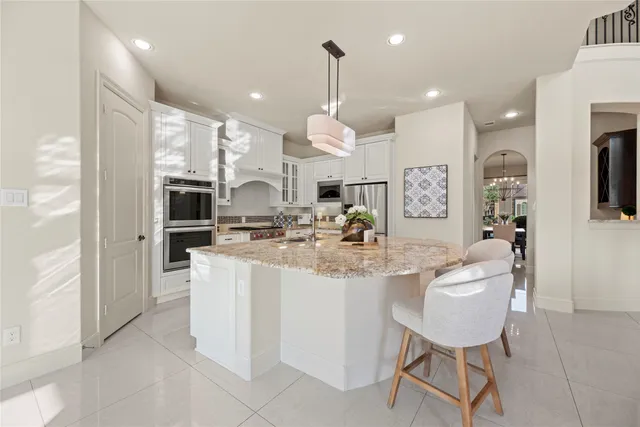 a kitchen with stainless steel appliances kitchen island granite countertop a sink and a refrigerator