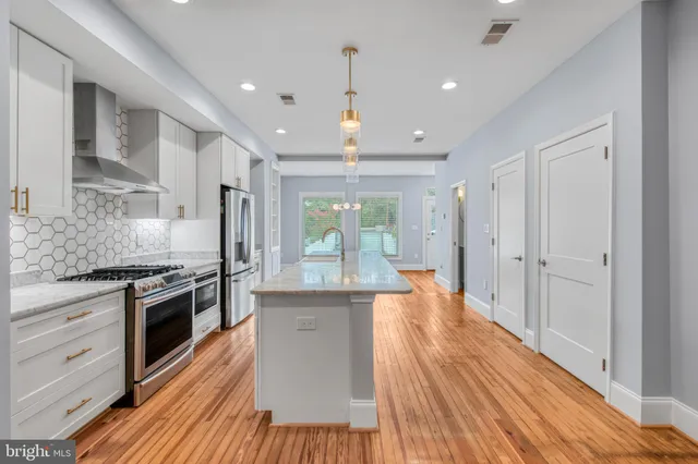 a large kitchen with stainless steel appliances granite countertop a stove and a wooden floors