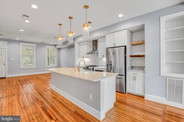 a large kitchen with stainless steel appliances granite countertop a refrigerator a oven and a cabinets with wooden floor