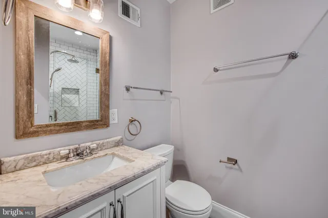 a bathroom with a granite countertop sink toilet a mirror and shower