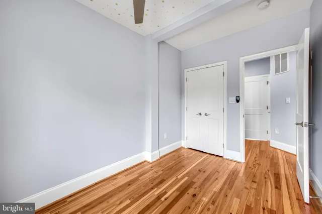 a view of a room with wooden floor and a ceiling fan