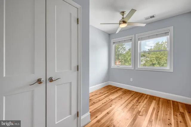 a view of empty room with wooden floor and fan