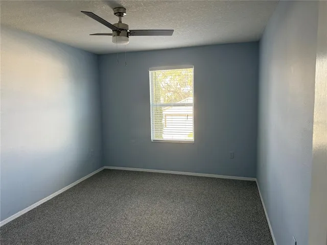 an empty room with a window and a fan