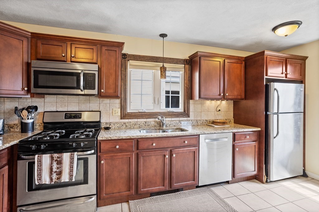 120 Goldsmith Street, Unit 3 Littleton, MA 01460 - Photo 6 of 33 a kitchen with stainless steel appliances granite countertop a stove microwave and refrigerator