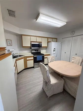 a room with stainless steel appliances kitchen island a cabinets and wooden floor
