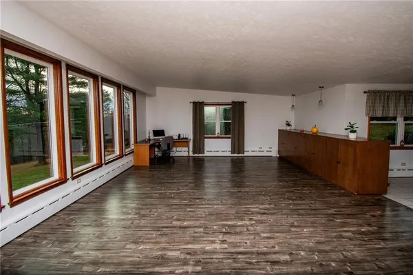 a view of an empty room with window and wooden floor