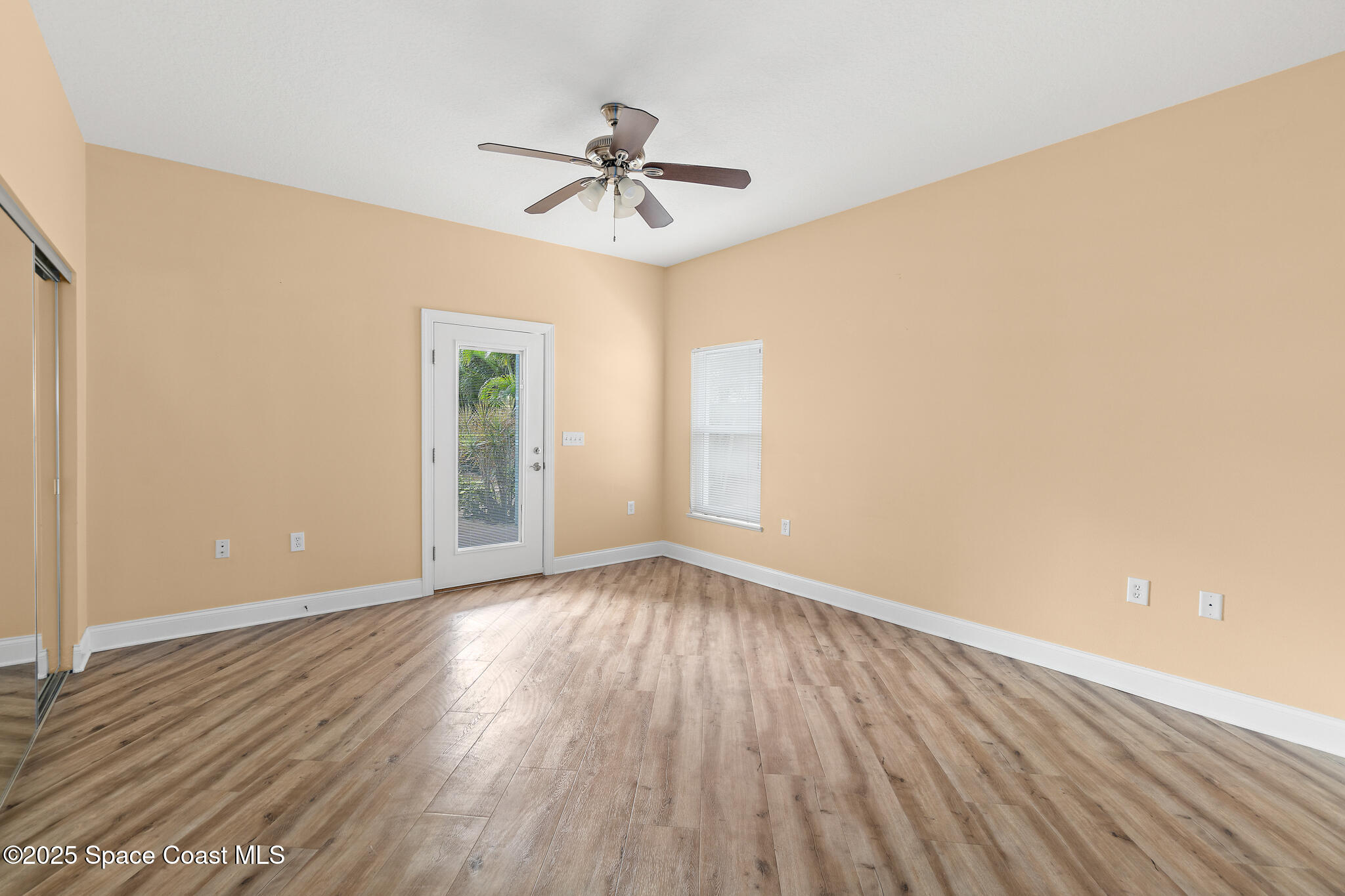 131 Harding Avenue, Unit 131 & 129 Cocoa Beach, FL 32931 - Photo 26 of 47 an empty room with wooden floor chandelier fan and windows