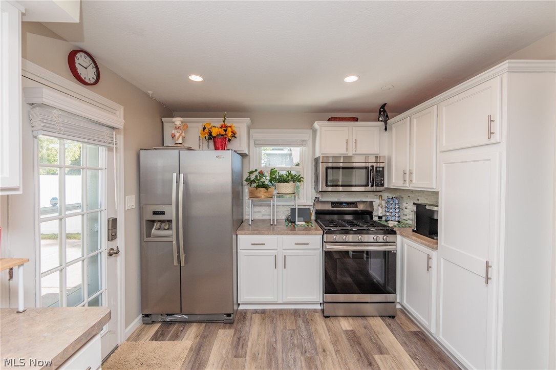 120 Sunset Road Avon Lake, OH 44012 - Photo 9 of 40 Kitchen featuring appliances with stainless steel finishes, light hardwood / wood-style flooring, white cabinetry, and tasteful backsplash
