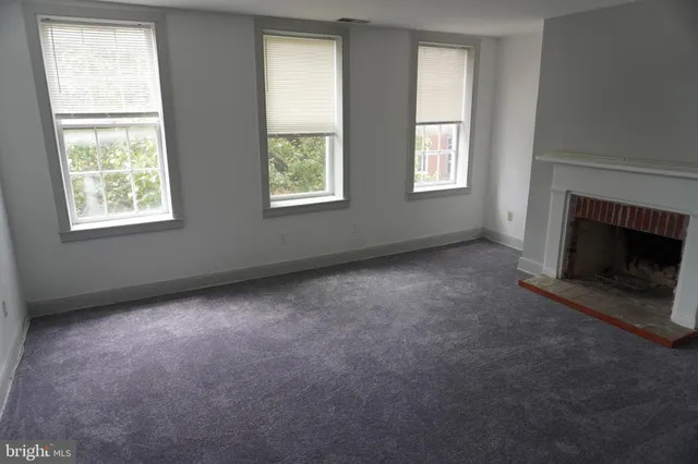 an empty room with windows and fireplace