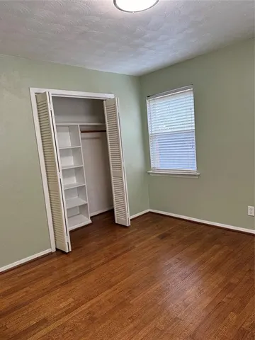 an empty room with wooden floor closet and windows