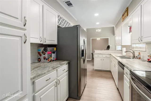a kitchen with a sink dishwasher a refrigerator and cabinets with wooden floor