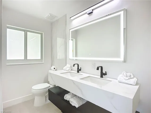 a bathroom with a toilet a sink a mirror and a window
