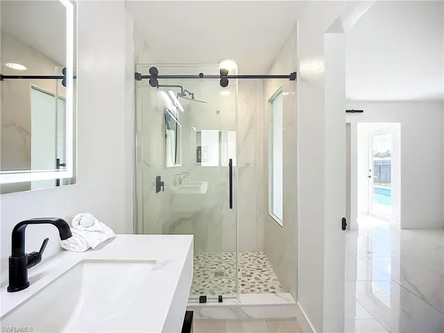 a bathroom with a sink vanity granite shower and a mirror