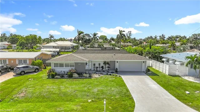 a view of a house with a big yard plants and large trees