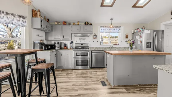 a kitchen with stainless steel appliances granite countertop a table chairs sink and cabinets