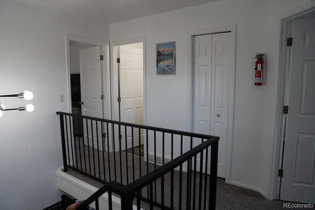 a view of a hallway with wooden floor and a bathroom