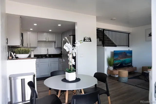 a kitchen with stainless steel appliances kitchen island granite countertop a dining table chairs and a refrigerator