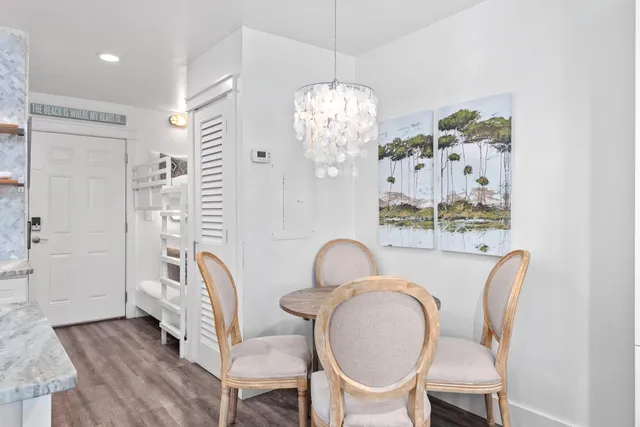 a dining room with wooden floor a chandelier a glass table and chairs