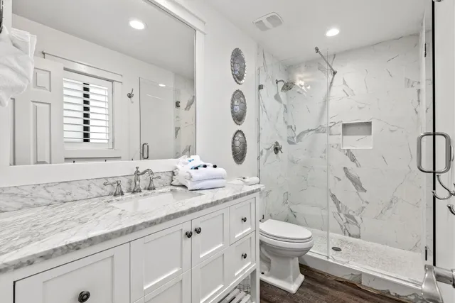 a bathroom with a granite countertop sink a toilet and a shower