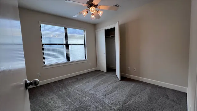 an empty room with chandelier fan and windows