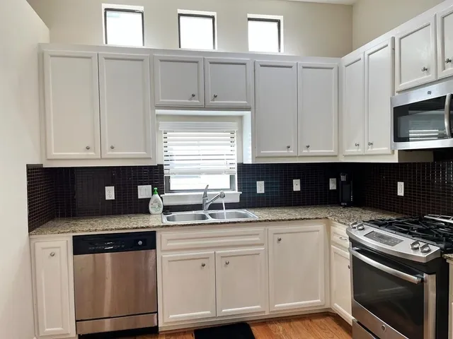 a kitchen with granite countertop a sink cabinets and stainless steel appliances